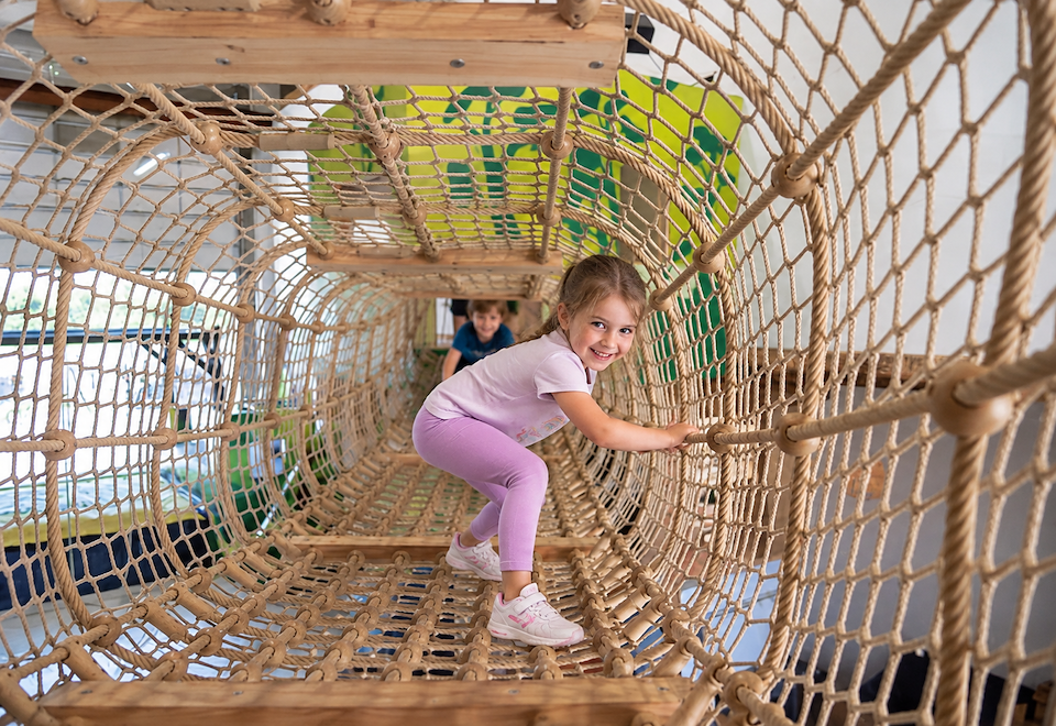 Kind im Klettertunnel des House of Explorado